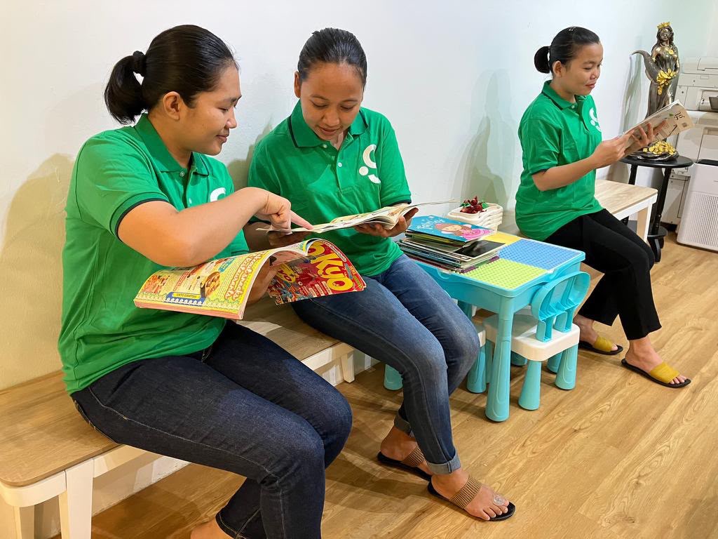 Domestic helpers placed through Green Employment, reading at the office